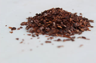 pile of dark cacao shells on white background