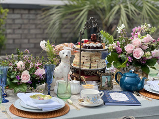 outdoor table with white linen, flowers, cake stand, tea cups