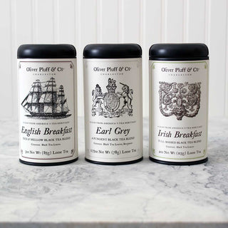 three black tea tins sitting in a row on white counter