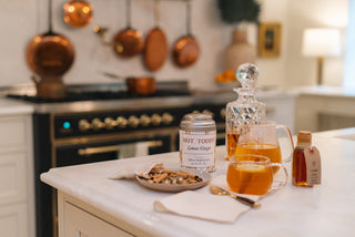 A kitchen counter with a glass of liquid and a plate of food.