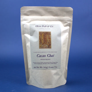 shiny white tea pouch bag with orange rectangle on label against a blue backdrop