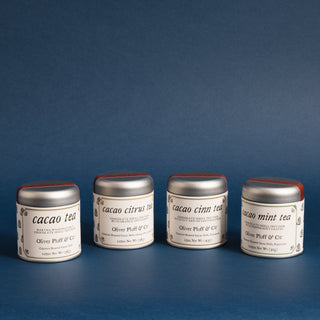 four small silver tea tins beside each other in a row against a blue backdrop