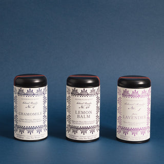 three black tea tins in a row with different colored labels, blue, black and pink