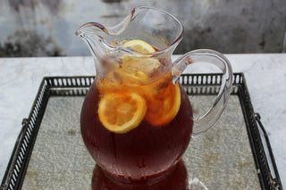 glass pitcher of iced tea with lemon slices on silver platter