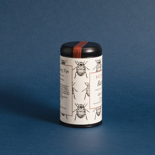 black tea tin with black and white lady bug pattern on label