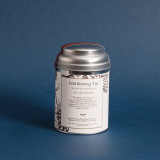 silver tea tin with blackberry graphics and brewing instructions with blue backdrop