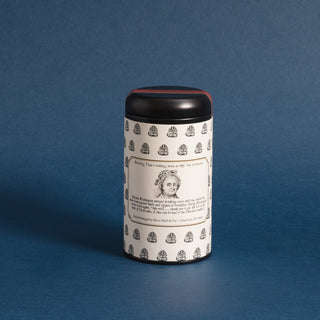 black tea tin with black and white sketches of cacao tea leaves and a sketch of Martha Washington face on label against blue background