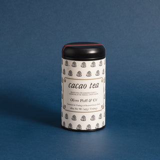 black tea tin with black and white sketches of cacao tea leaves against blue background