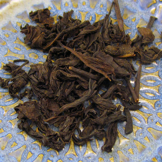 zoomed in phoeo of dark loose leaf tea on blue and yellow plate