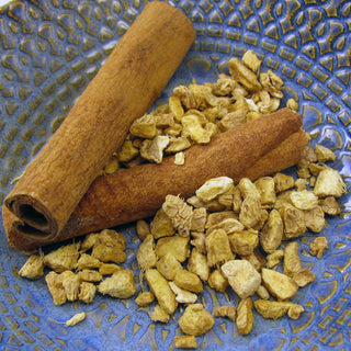 zoomed in view of 2 cinnamon sticks and loose leaf tea in blue bowl