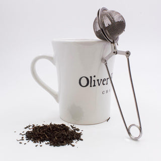 white mug with stack of tea leaves beside it andWire Mesh Tea Brewing Ball - Small 1.5" diameter ball with handle to seep and stir your tea!