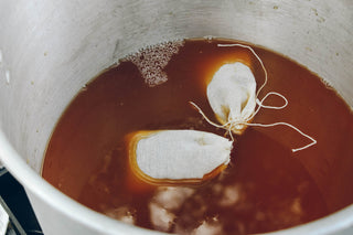 zoomed in view of brown tea with bubbles and two white tea bags floating