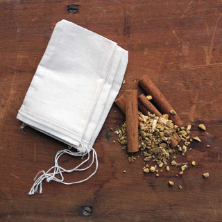 white tea bags, cinnamon sticks and loose leaf tea on wood table