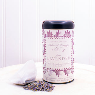  black tea tin with purple pattern on label sitting beside pile of loose leaf lavender tea and white mesh tea bag