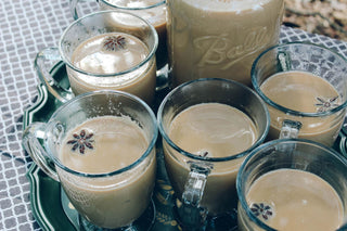 6 clear glasses filled with chai tea sitting on a silver platter