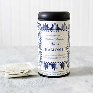 black tea tin with blue designs on label beside stack of white mesh tea bags sitting on white counter