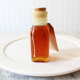 small rectangular glass honey jar with cork sitting on white plate