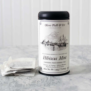 black tea tin with old timey ships on label beside 3 white meshed tea bags on kitchen counter