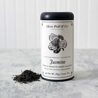 black tea tin with black and white flower on label beside small pile of loose leaf tea sitting on kitchen counter