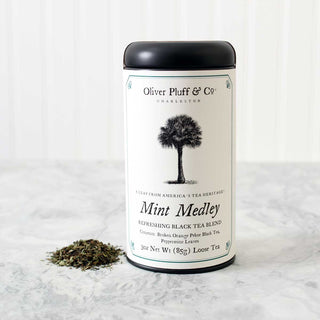 black tea tin with image of tree on label sitting beside small pile of loose leaf tea