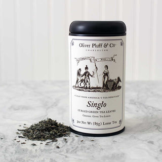 3oz loose tea, sealed in matte black signature tea tin beside loose leaf tea on white counter